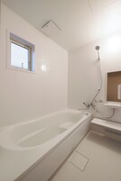 Un baño moderno con bañera, ventana y ducha.