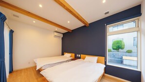 Ein Hotelzimmer mit zwei Betten, Holzbalken, einem großen Fenster und Blick nach draußen.