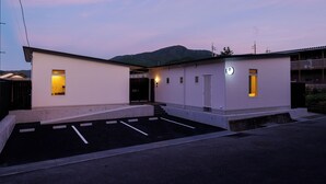 Ein modernes Gebäude mit Parkplatz, einem kleinen Eingang und einer sichtbaren Tür.