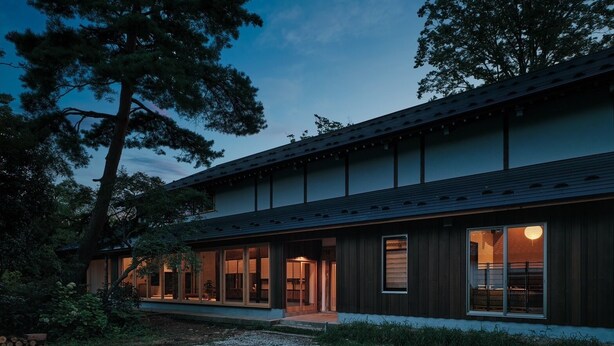 Un bâtiment moderne à deux étages, doté de grandes fenêtres, d’un porche couvert et d’une allée gravillonnée.
