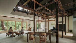 Une pièce spacieuse dotée de grandes fenêtres, de poutres en bois et d’un plafond haut.