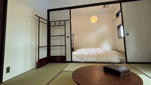 Une pièce de style japonais traditionnel, avec un sol recouvert de tatamis, une petite table en bois et des portes coulissantes donnant sur une autre pièce.