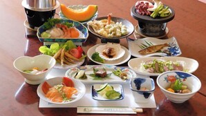 Variedad de platos en una mesa, como sushi, sashimi y verduras.