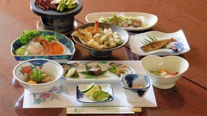Variedad de platos sobre una mesa, incluyendo un caldo hirviendo, sashimi y otras especialidades japonesas.