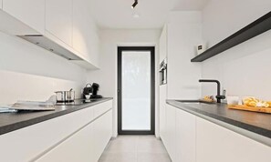 Cocina moderna con armarios blancos, encimera negra y grifo negro.