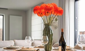 Una mesa de comedor con un florero, botellas de vino y copas de vino vacías.