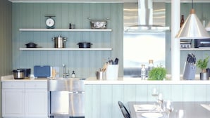 A modern kitchen with stainless steel appliances, a built-in oven, and a dining area with a table set for two. - Glamday Port Sea-view Hill (Atami)