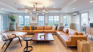 A spacious living room with a large sofa, a coffee table, and a TV stand. - Glamday Port Sea-view Hill (Atami)