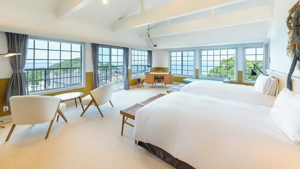 A hotel room with two large beds, a desk, a chair, and a view of the sea. - Glamday Port Sea-view Hill (Atami)