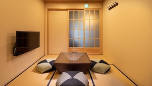 A tatami mat room with a low table, cushions, a television, and a shoji screen door. - Tsumugi Horikawa Kichimonji (Kyoto)
