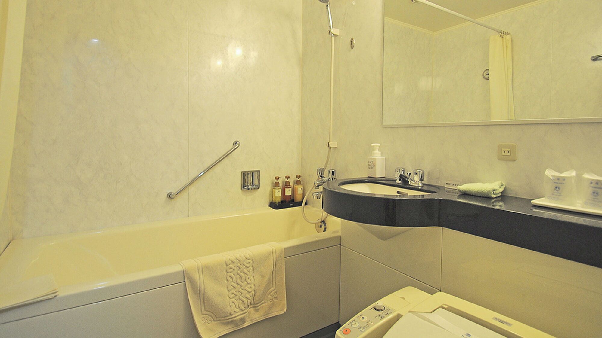 A bathroom with a bathtub, a sink, a mirror, and toiletries.