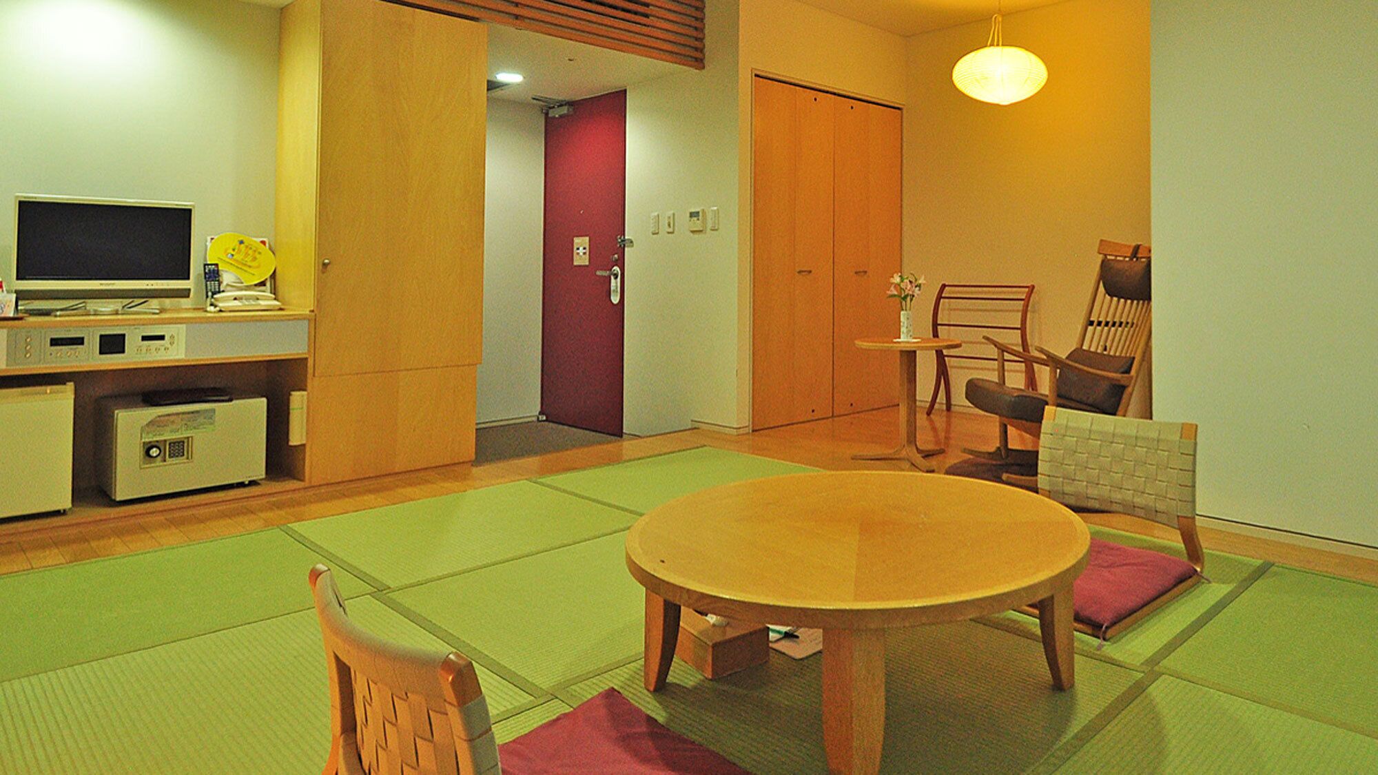 A traditional Japanese-style room with tatami flooring, a low table, and a seating arrangement.