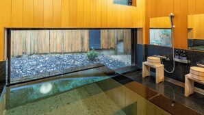 A modern bathroom with a large window, a small wooden stool, and a shower area. - Glampetit Koh (Atami)