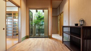 A hallway with wooden flooring, a sliding glass door leading to a garden, and a traditional Japanese sliding door on the left. - Glampetit Koh (Atami)