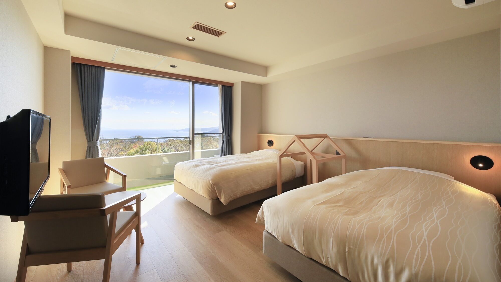 A hotel room with two beds, a desk, a chair, and a large window with a view.