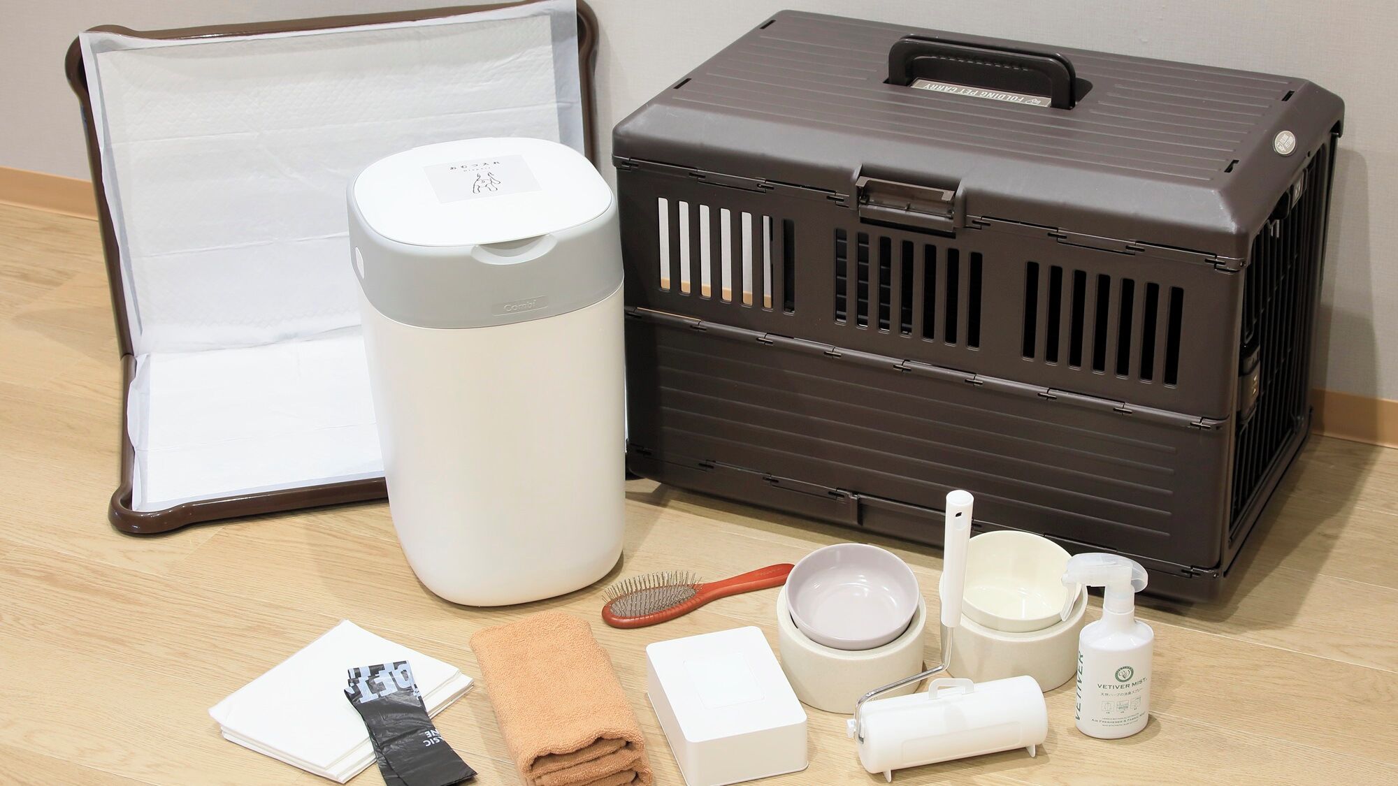 A travel case with a handle, a white cylindrical container, a brown case with ventilation slits, a hairbrush, a towel, a white box, a bowl, a cup, and a bottle.