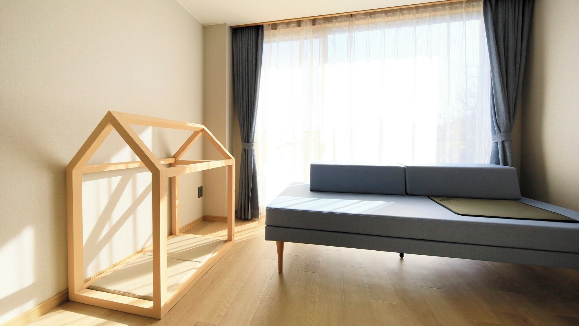 A room with a wooden bed frame, a sofa, and a window with curtains.