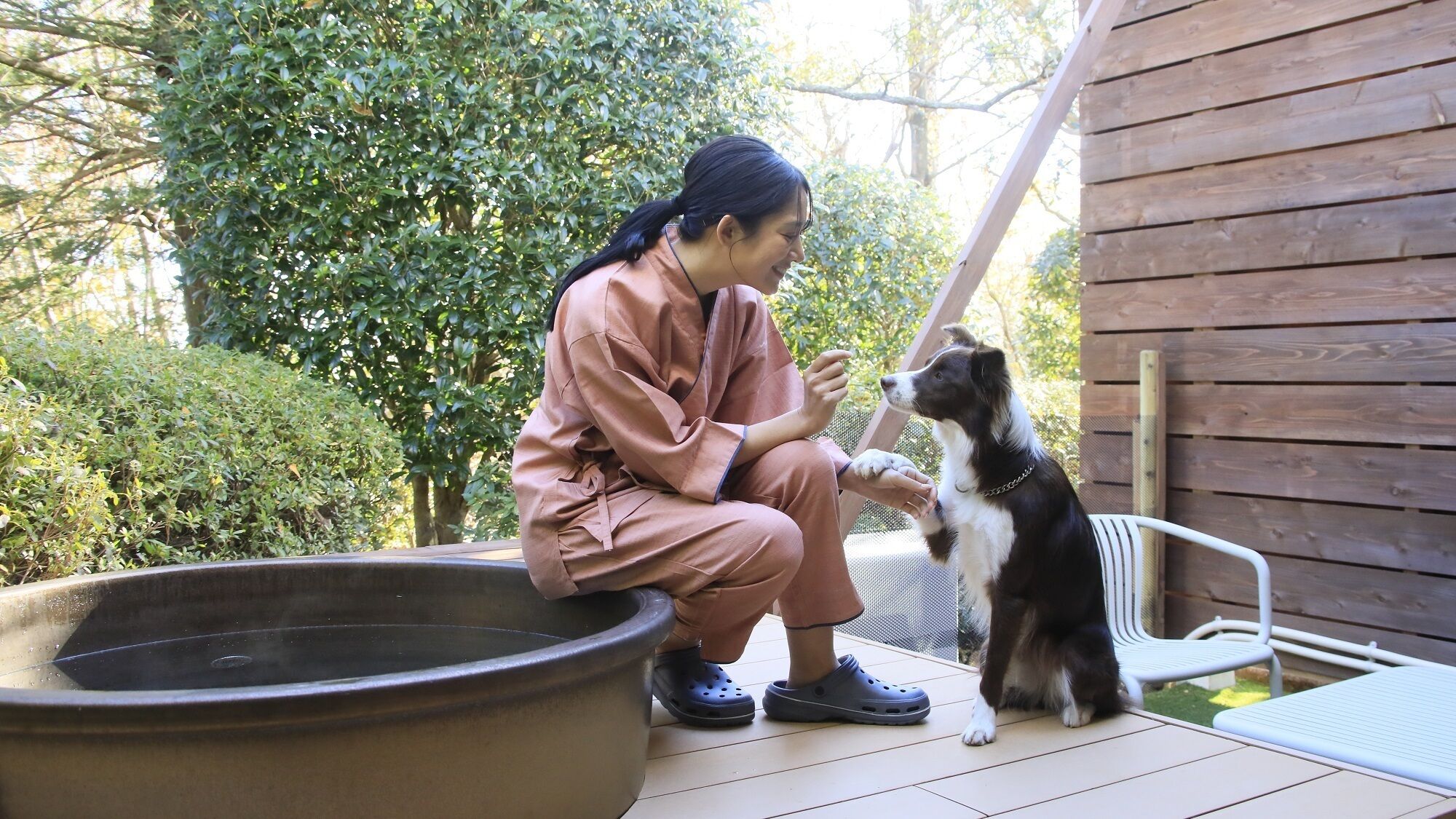 A person in pink attire sitting on a patio with a dog.