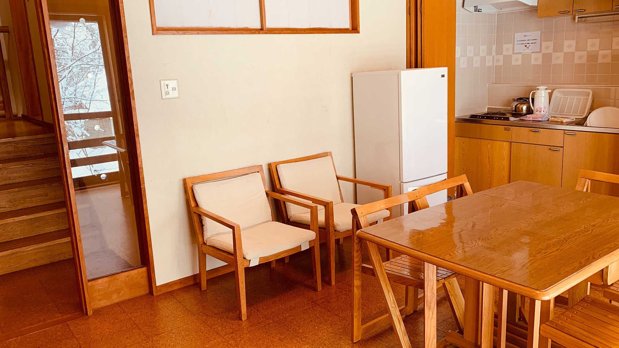 Una cucina compatta con mobili in legno, un frigorifero bianco e un tavolo da pranzo con sedie.