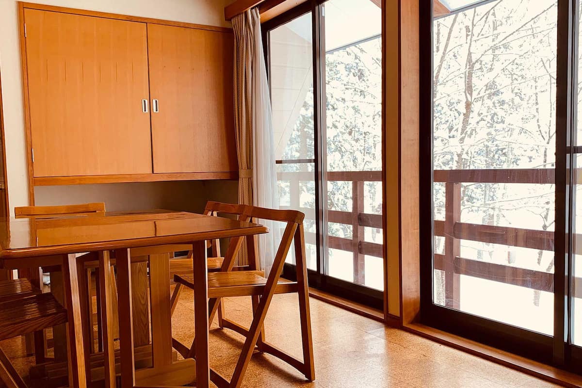 Ein Holzespeisesaal mit Stühlen, ein Holzschrank und ein großes Fenster mit Blick auf Bäume.