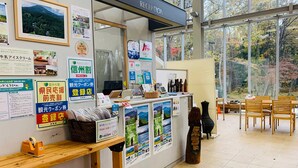 Een receptie met een balie, informatieposters en uitzicht op bomen door grote ramen.