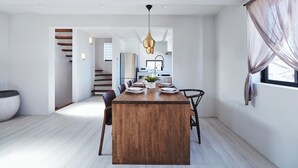 A modern dining area with a wooden table, chairs, and a hanging light fixture. - &moon Noa (Tokyo)