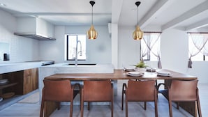 A modern kitchen with a central island, wooden chairs, and pendant lighting. - &moon Noa (Tokyo)