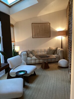 Ein modernes Wohnzimmer mit einer Couch, Sesseln, einem Couchtisch und einer Lampe.