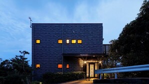 A modern building with a dark facade, multiple windows, and a well-lit entrance. - Glampetit Horizon (Atami)