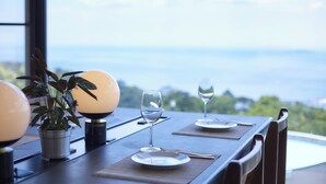A dining table with two wine glasses, a potted plant, and a view of the landscape. - Glampetit Horizon (Atami)