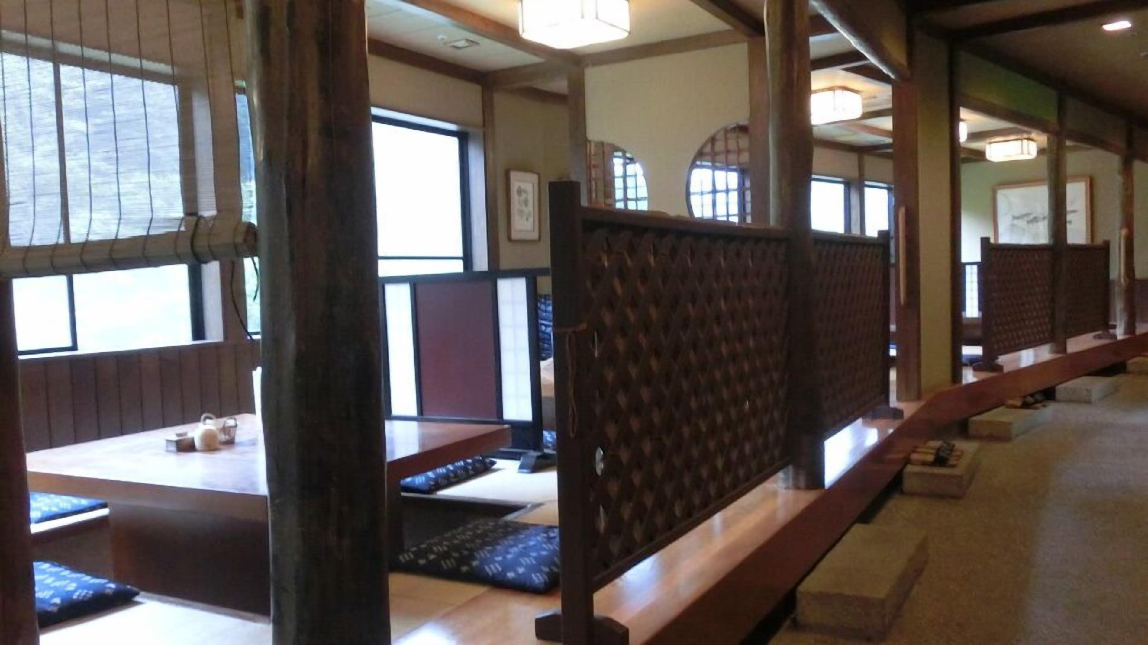 A traditional Japanese-style room with tatami mat flooring, low wooden tables, and sliding doors.