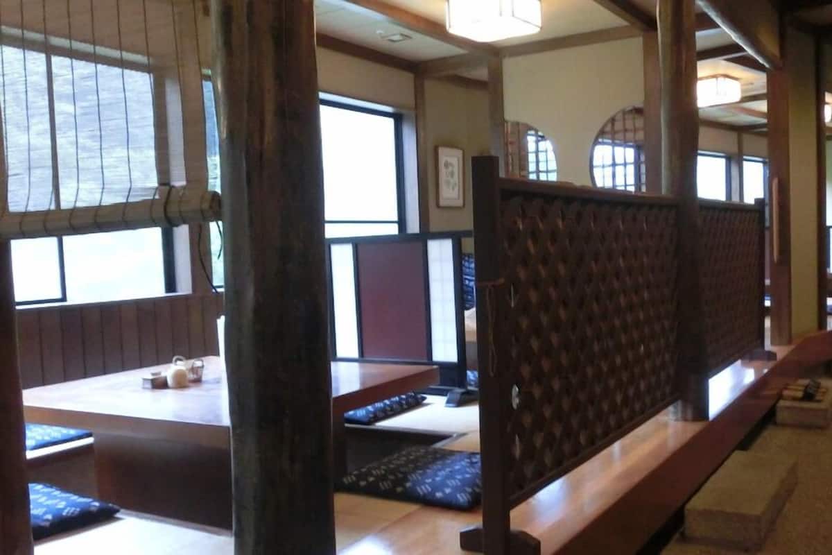 A traditional Japanese-style room with tatami mat flooring, low wooden tables, and sliding doors.