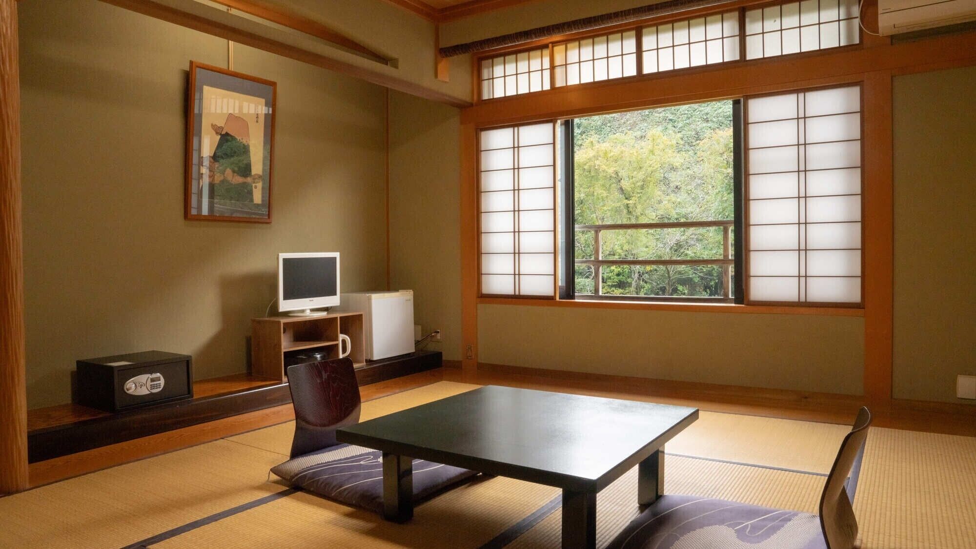 A traditional Japanese room with tatami flooring, a low table, a television, and a refrigerator.
