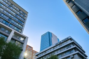Ein modernes Hotelgebäude mit mehreren Etagen, großen Fenstern und einem gut sichtbaren Schild mit der Aufschrift 'Airbnb hotel'.