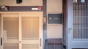 A traditional Japanese gate with sliding doors, a small sign with Japanese characters, and a wall-mounted mailbox.