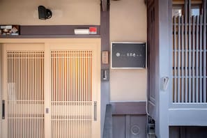 A traditional Japanese gate with sliding doors, a small sign with Japanese characters, and a wall-mounted mailbox. - Kyoto Machiya Kichiatsuse Umekoji (Kyoto)