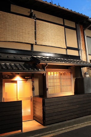 En traditionell japansk byggnad med golv av tatamimattor, en skjutdörr och en träbänk utanför.