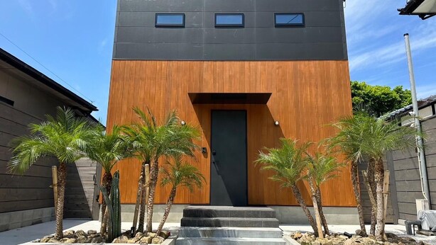 Ein modernes Gebäude mit dunkler Fassade, einem hölzernen unteren Bereich und einem zentralen Eingang mit Stufen.