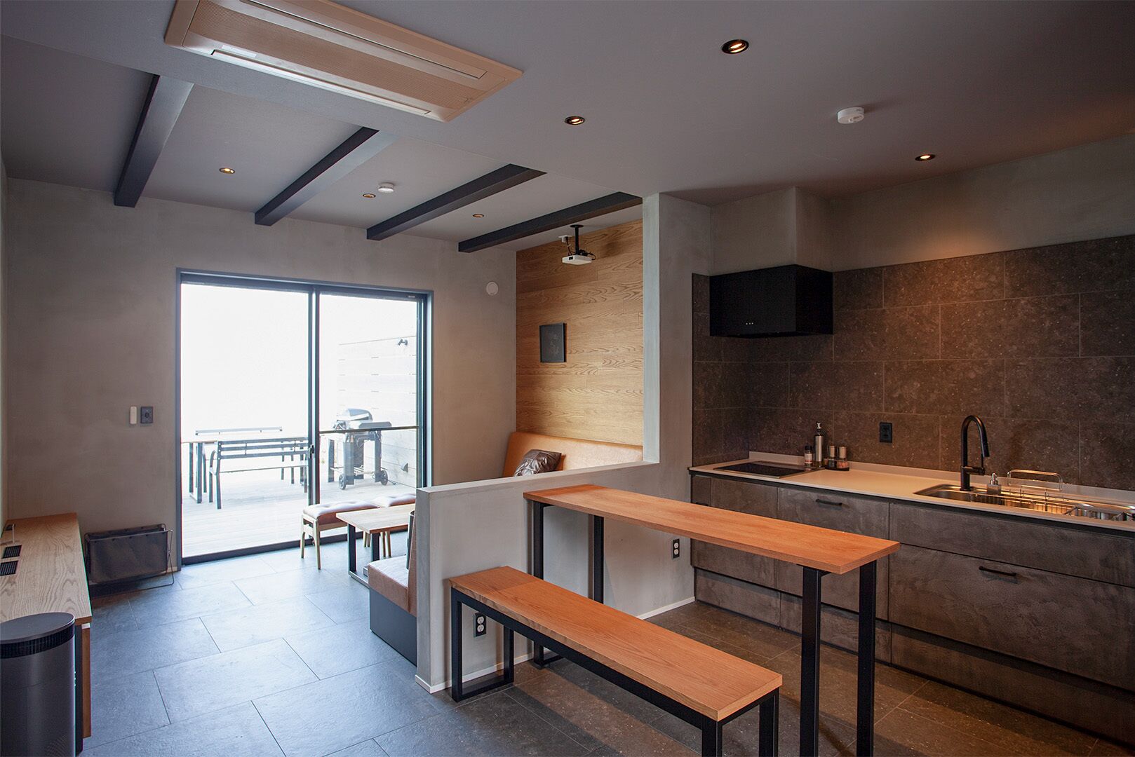 A modern kitchen with a built-in stove, a sink, and a wooden bench.