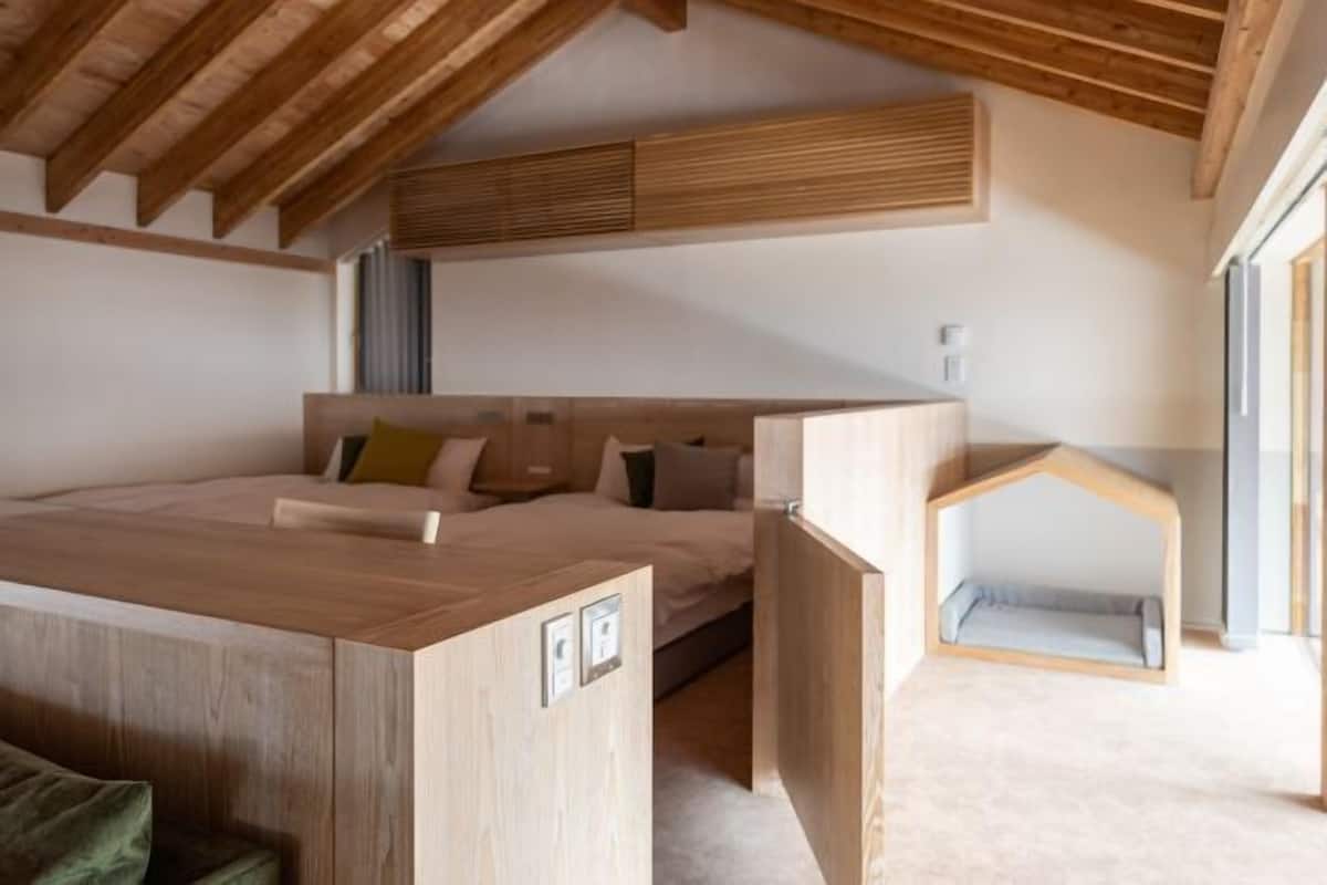 Un dormitorio con techo de madera, cama, escritorio y una cama para un niño pequeño.