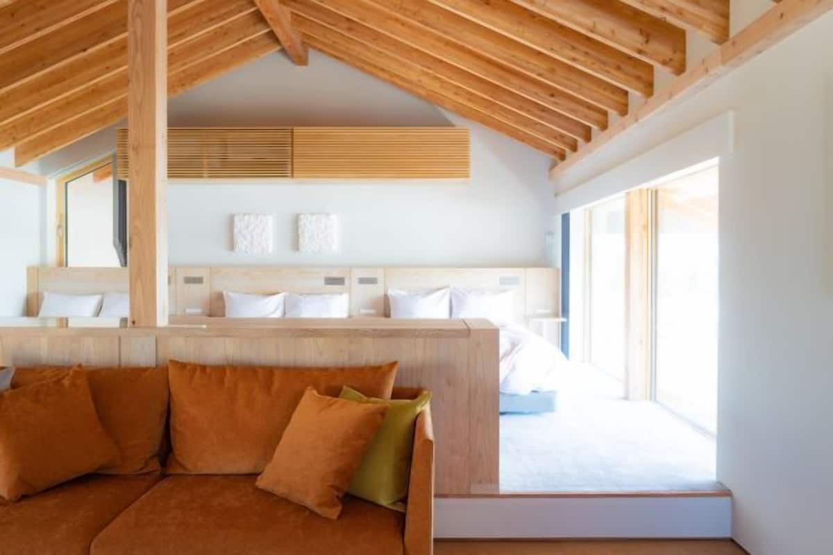 Un dormitorio con techo de madera, una cama con ropa blanca y un sofá con cojines.