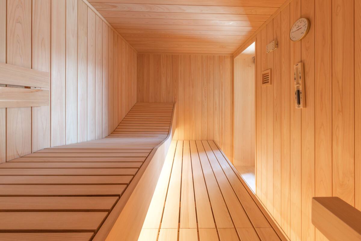 Una sauna de madera con suelo inclinado que lleva a una zona central, paredes de madera y un reloj en la pared.