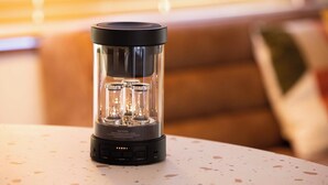 A portable air purifier with a black base and transparent filter housing, placed on a speckled table. - Maigre Fields (Atami)