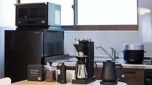 A kitchen with a microwave, coffee maker, and coffee pot on the counter. - Maigre Fields (Atami)