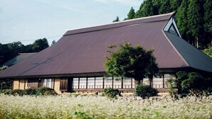 Een traditioneel Japans gebouw met een schuin dak, omgeven door een veld witte bloemen.