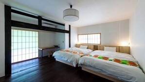 Een slaapkamer met twee bedden, een bureau en een groot raam.