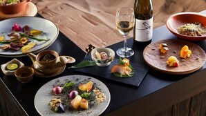 Een eettafel met diverse gerechten, een wijnfles en een theepot.