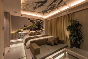 A modern bedroom with a bed, sofa, and a large potted plant. - Hotel Minato (Tokyo)