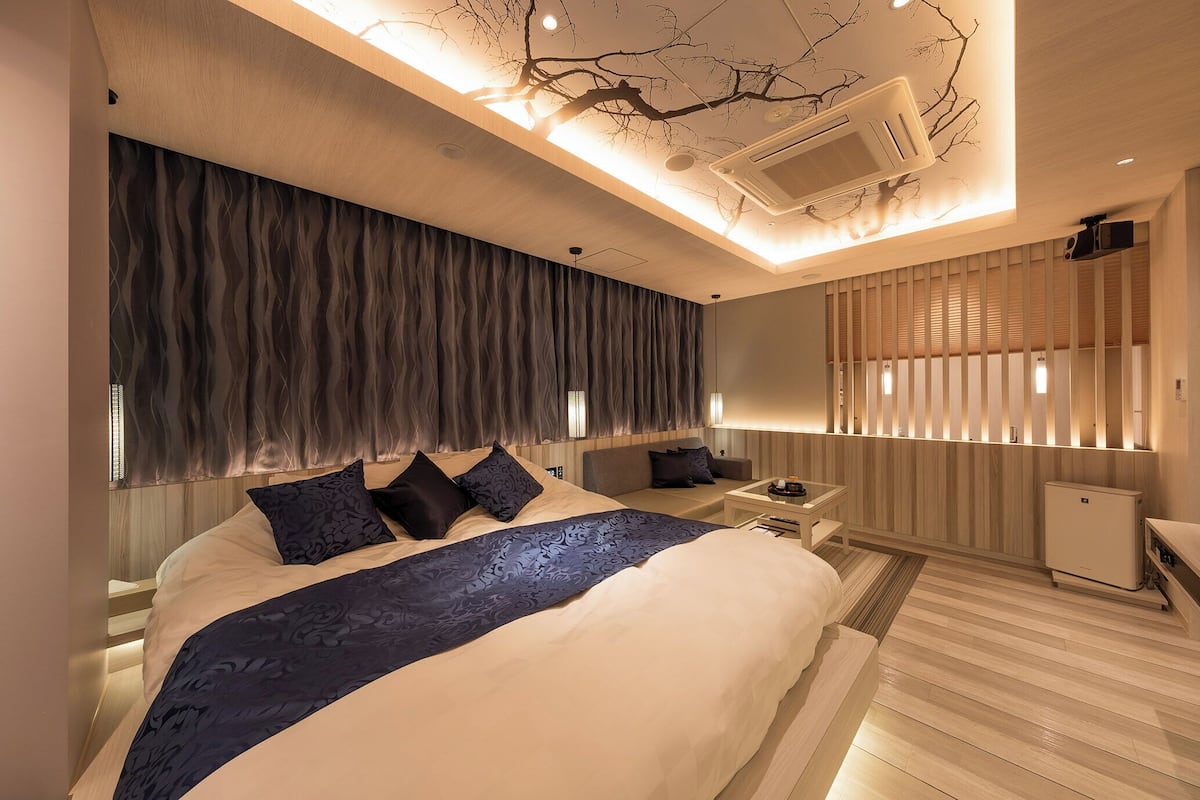 A modern hotel room with a large bed, bedside tables, a desk, and a built-in heater.