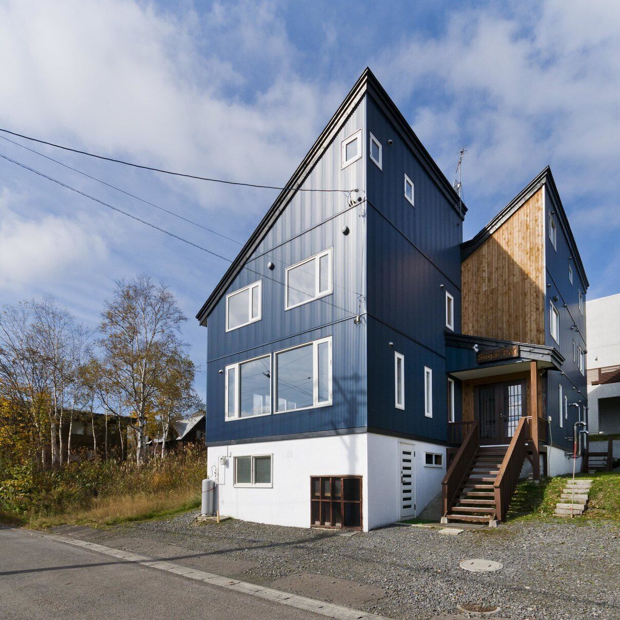 A modern two-story building with a wooden staircase leading to the entrance.
